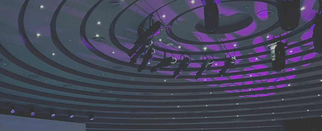 The Ceiling Of An Auditorium With Lights And Pink Lighting.