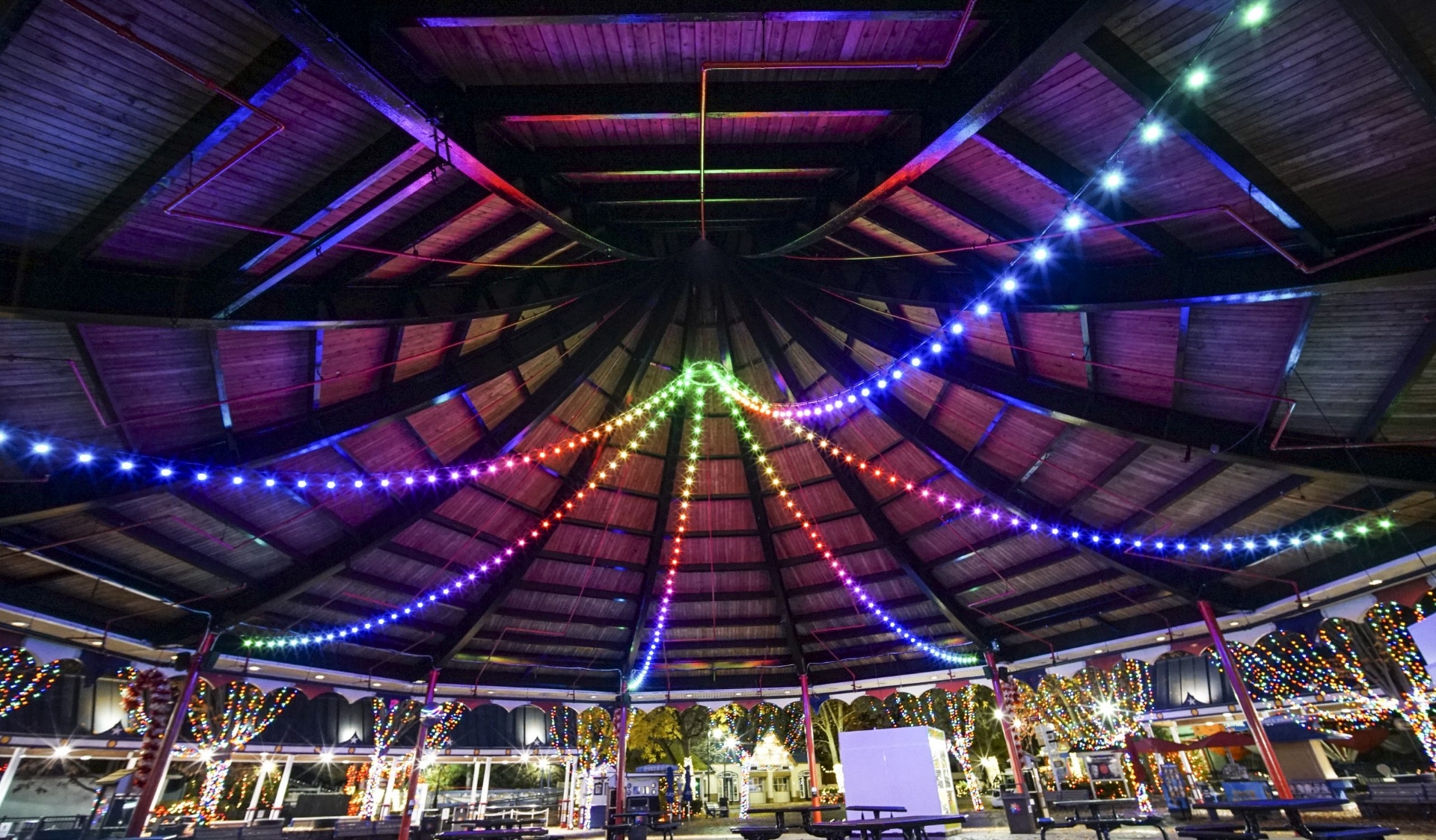 A Party Venue With High Wood Ceilings And Colored Neon String Lights.