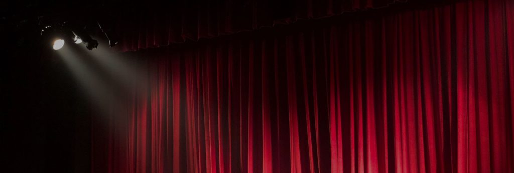 Red Curtains With A Light Shining On Them.