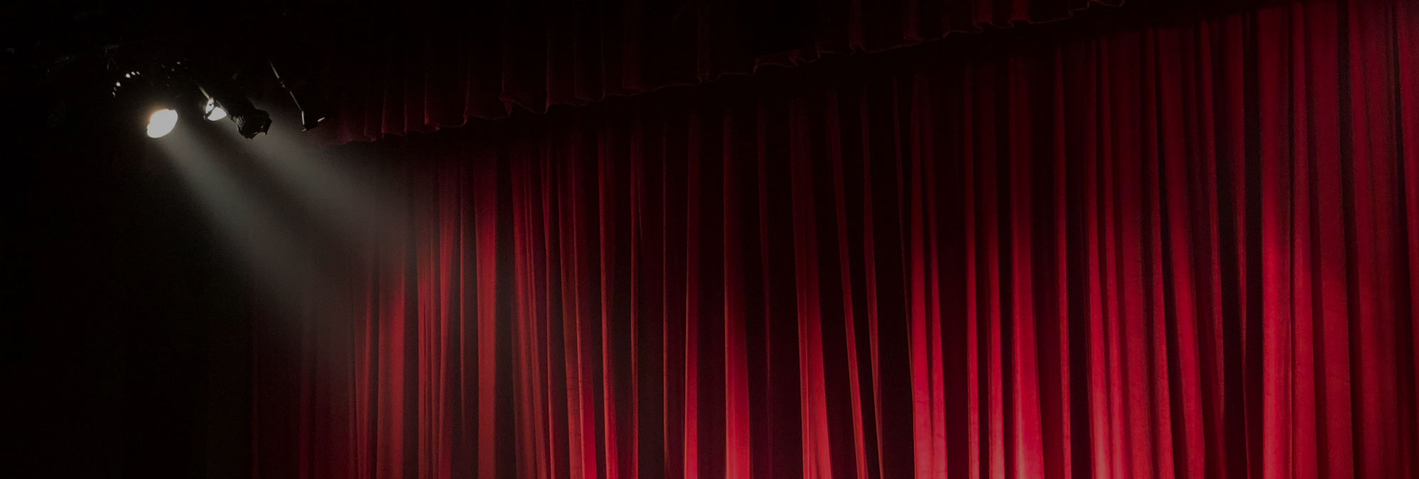 Red Curtains With A Light Shining On Them.
