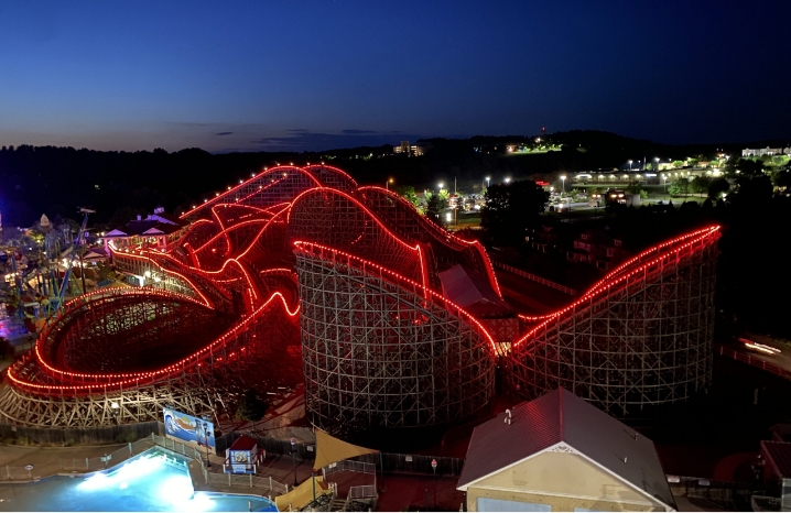 A Large Roller Coaster With Red Neon Lights.