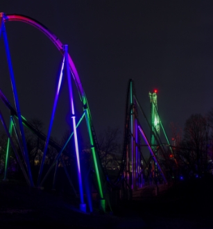 A Roller Coaster Track With Neon Lights Illuminating The Dark.
